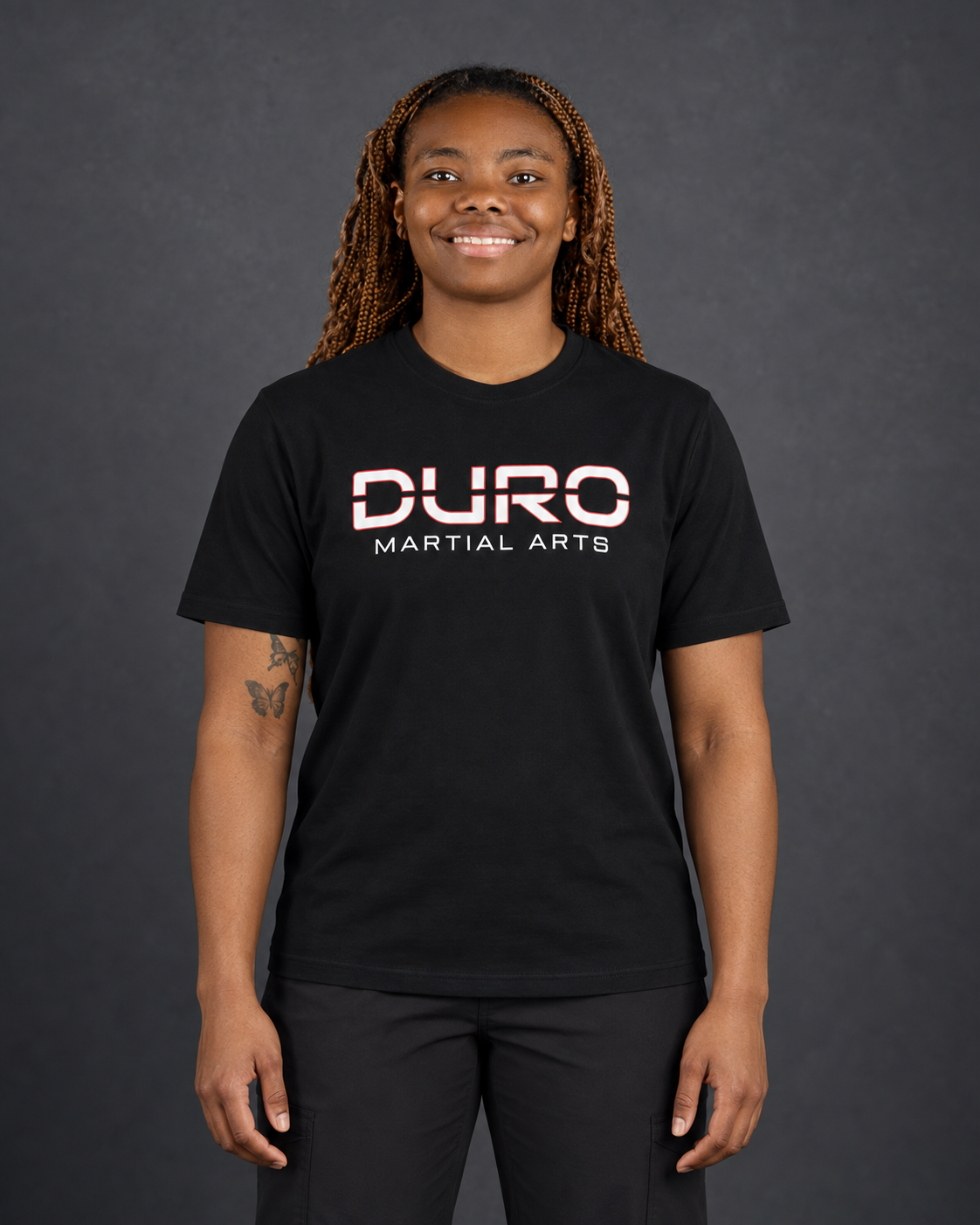 Coach Kaheil Mishoe-Elliott modeling the black DURO Martial Arts Under Armour® Performance Tee — AI-assisted studio image