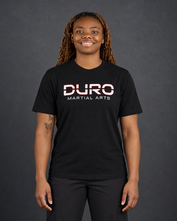 Coach Kaheil Mishoe-Elliott modeling the black DURO Martial Arts Under Armour® Performance Tee — AI-assisted studio image