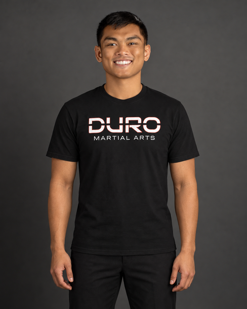 Coach TJ Hernandez modeling the black DURO Martial Arts Everyday Tee — AI-assisted studio image