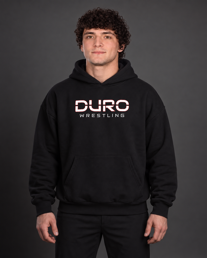 Tanner modeling the black DURO Wrestling Heavyweight Hoodie — AI-assisted studio image