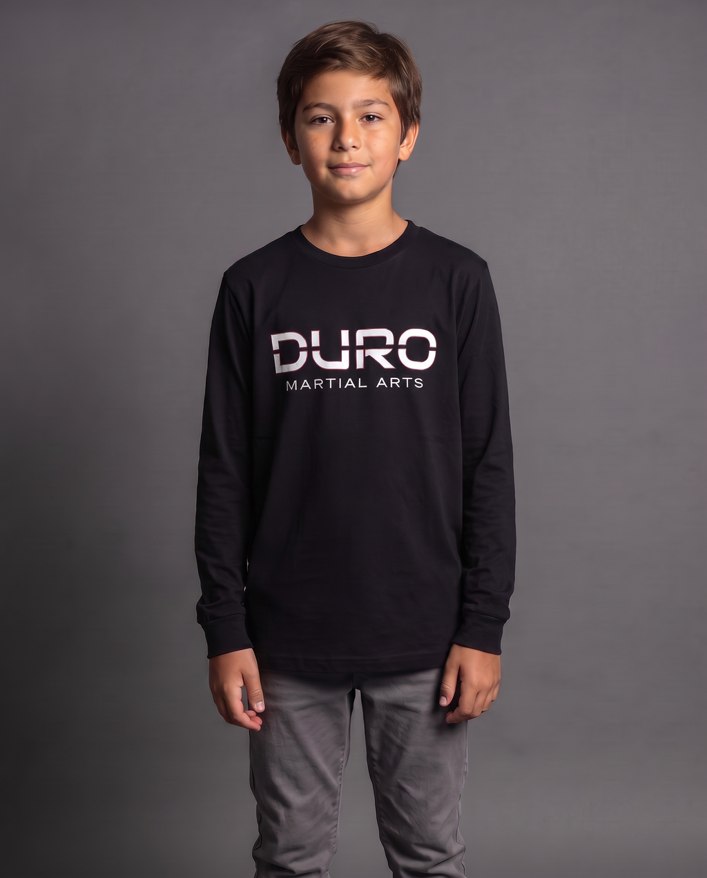 DURO Youth Martial Arts Long Sleeve Tee modeled against a charcoal studio background — AI-generated styling image