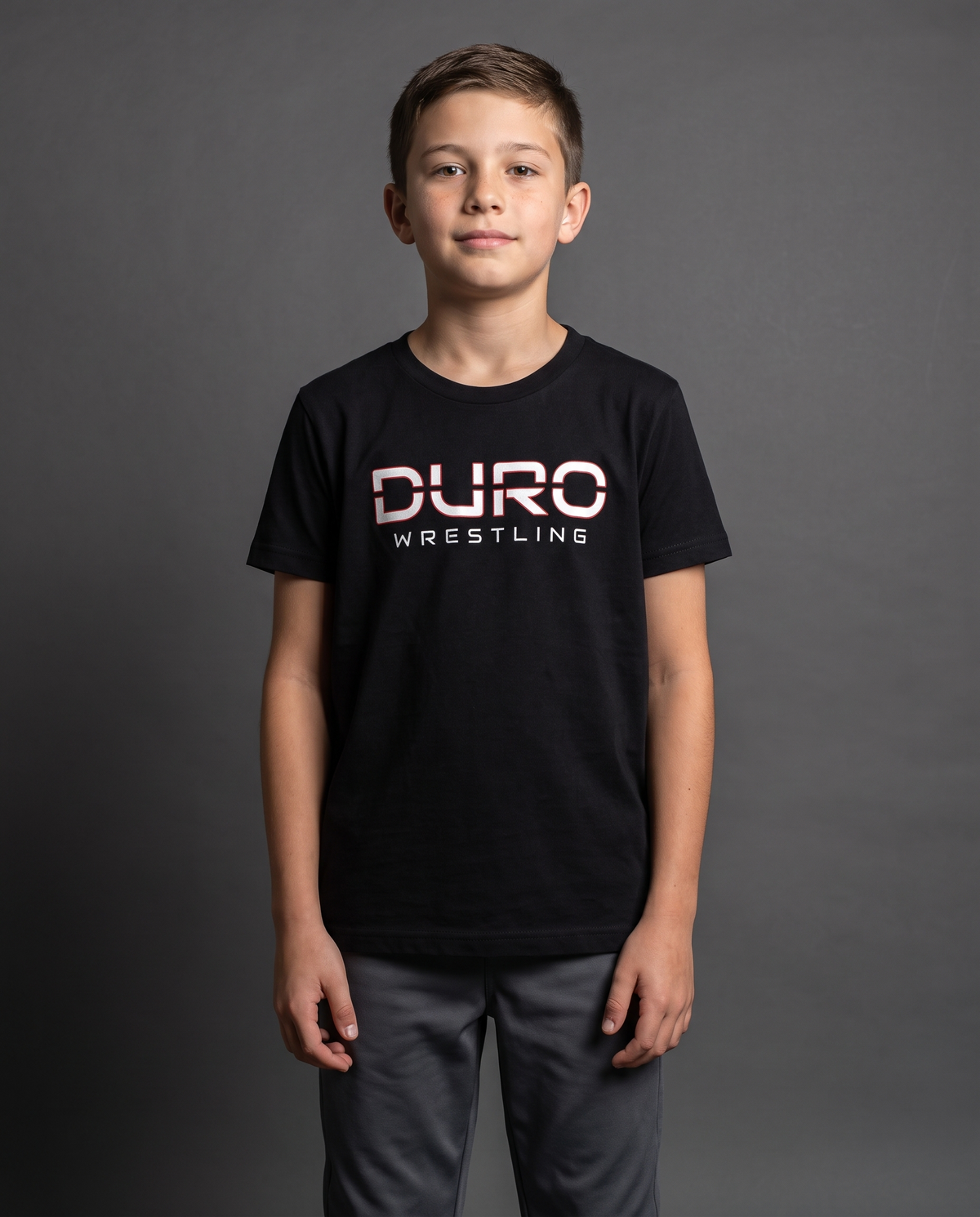 DURO Youth Wrestling Everyday Tee modeled against a charcoal studio background — AI-generated styling image